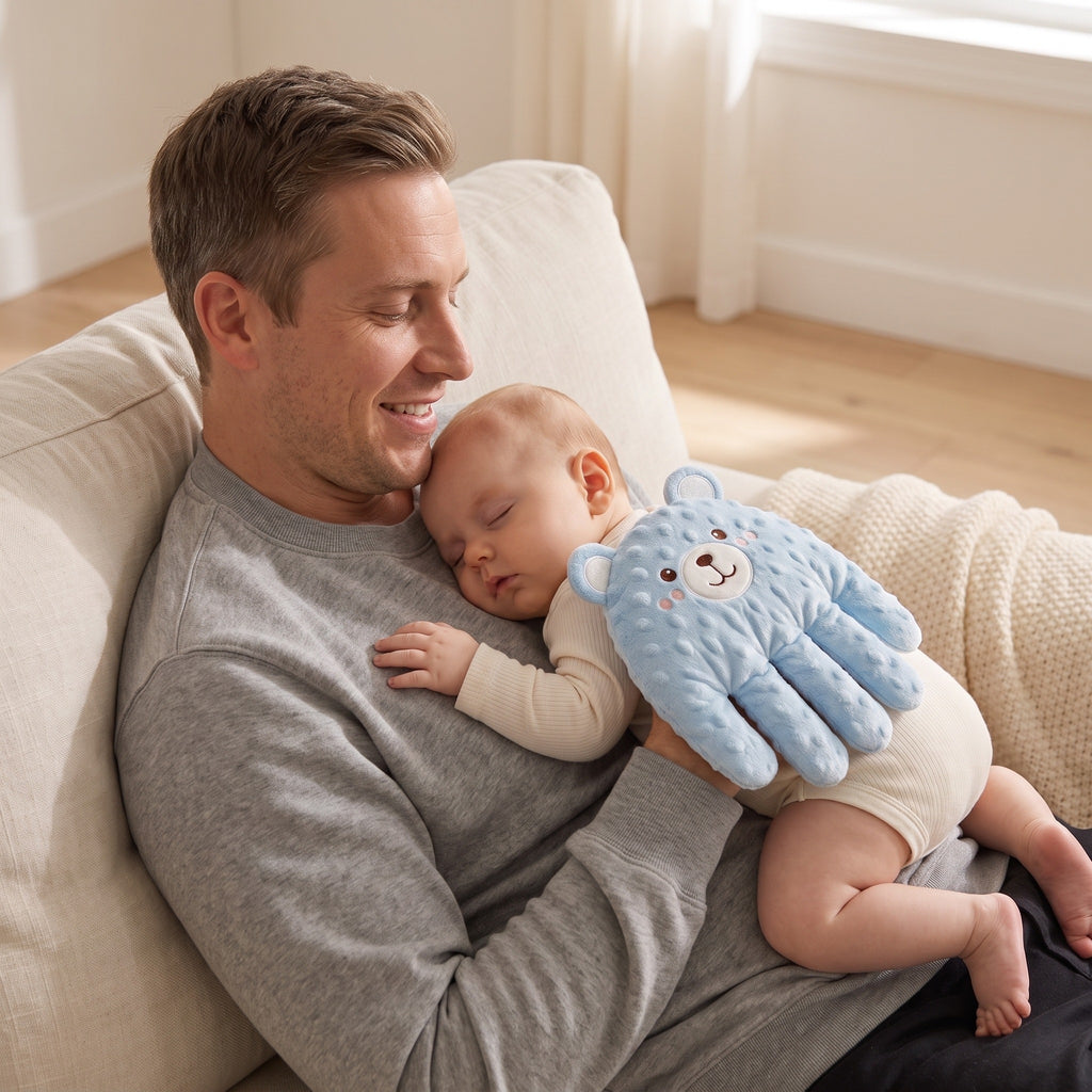 Father cuddling a sleeping baby with the blue patting hand on the sofa
