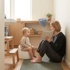 Toddler on a potty while a parent reads a picture book