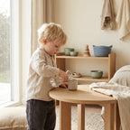 Toddler pouring water from a small jug at a low table